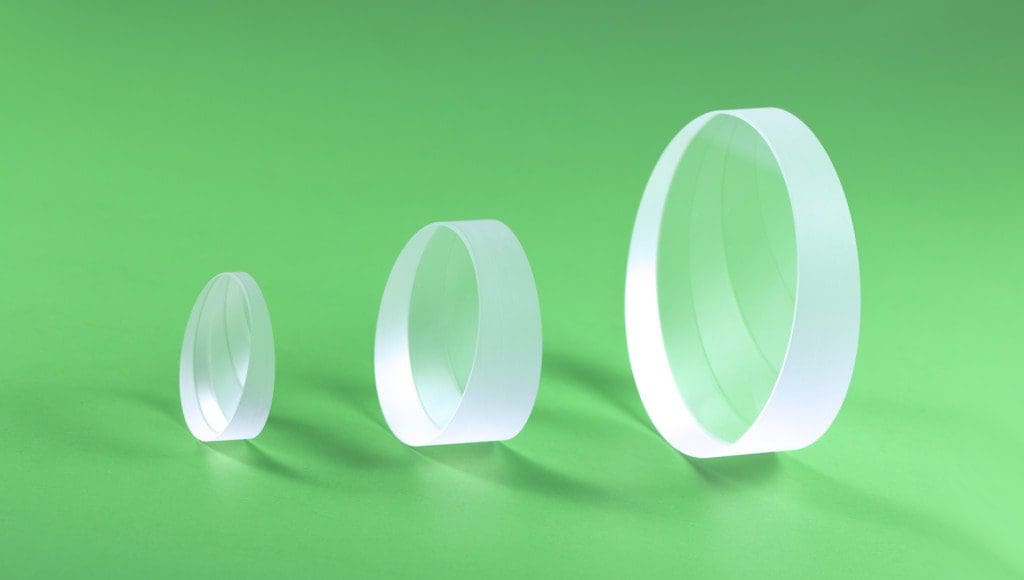 Three glass lenses on green background.