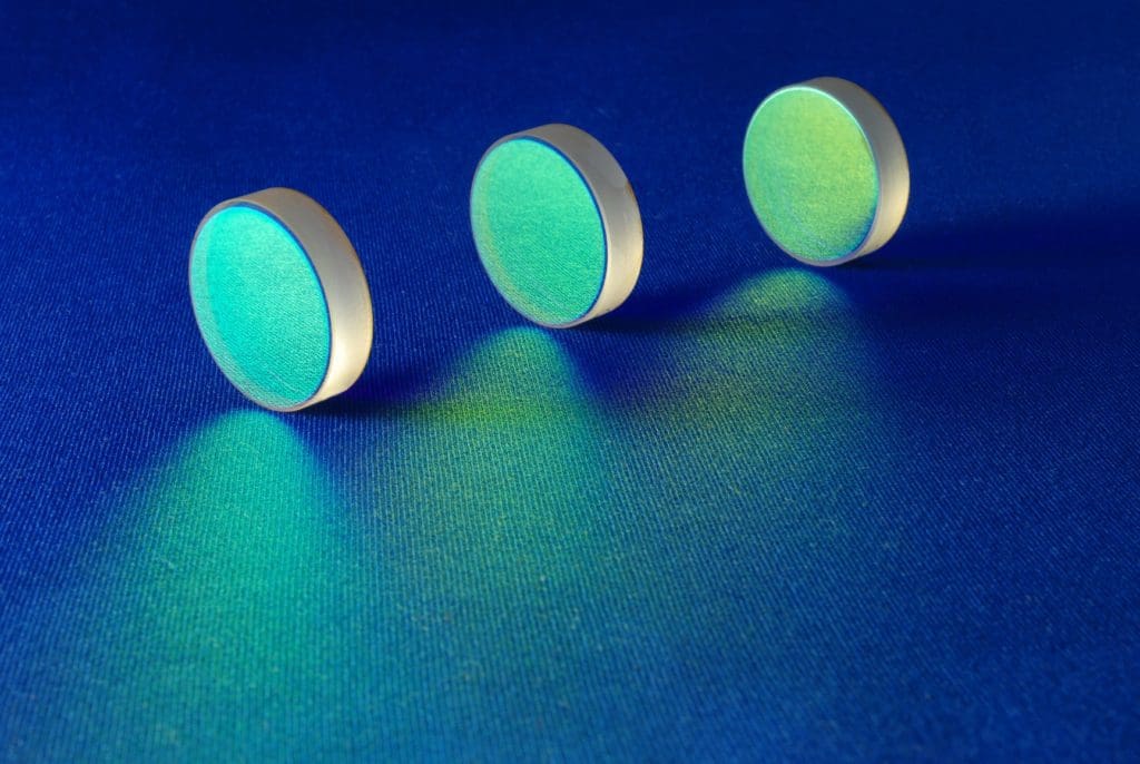 Three iridescent optical lenses on blue.